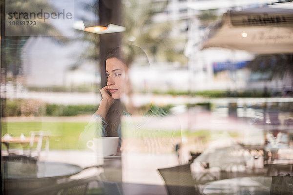 Frau blickt hinter reflektierendes Cafe-Fenster  Dubai  Vereinigte Arabische Emirate