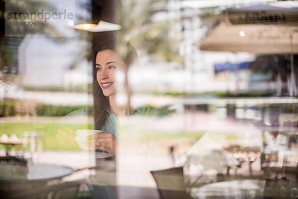 Glückliche Frau hinter reflektierendem Cafe-Fenster  Dubai  Vereinigte Arabische Emirate