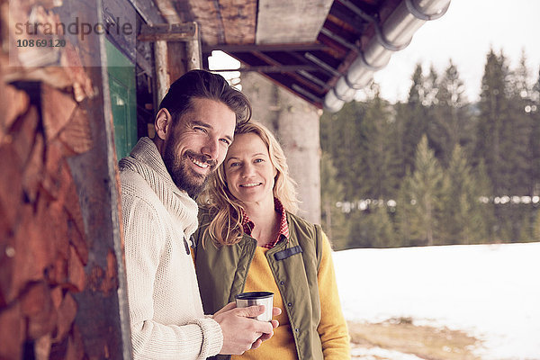 Porträt eines Ehepaares  das im Winter vor einem Blockhaus steht  Elmau  Bayern  Deutschland