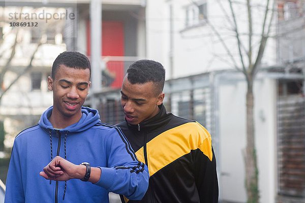 Zwillingsbrüder gehen die Straße entlang und schauen auf die Uhr