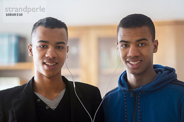 Porträt der Zwillingsbrüder  die sich Kopfhörer teilen
