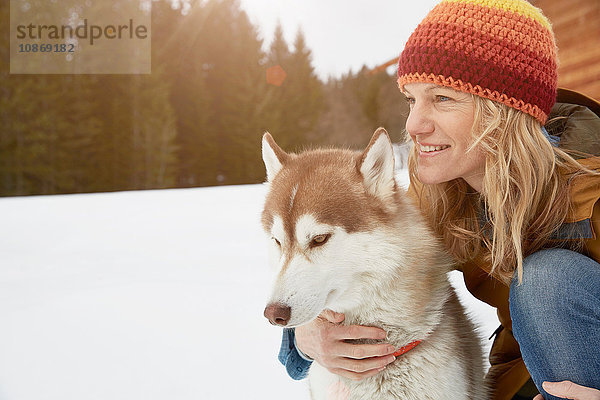 Frau kniend mit Husky in schneebedeckter Landschaft  Elmau  Bayern  Deutschland