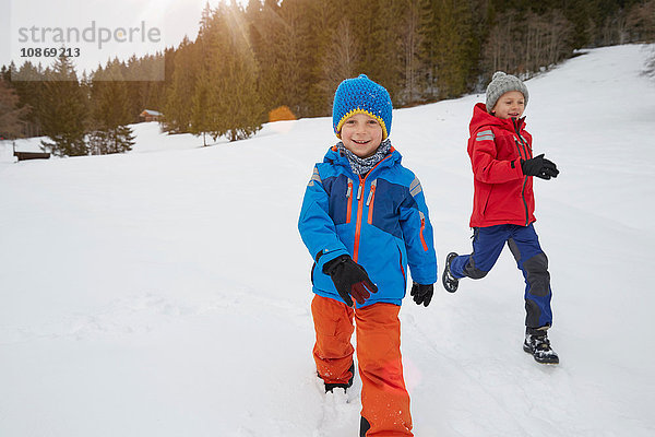 Junge und Bruder laufen in schneebedeckter Landschaft  Elmau  Bayern  Deutschland