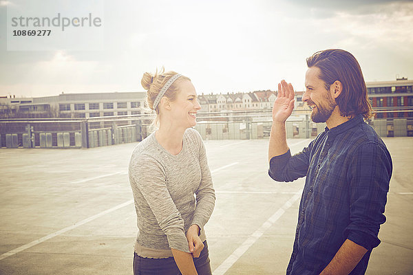 Mittelgroßes erwachsenes Paar gibt High Five auf dem Dachparkplatz