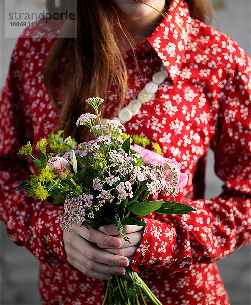 Geschnittene Aufnahme einer Frau in roter Bluse mit einem Blumenstrauss