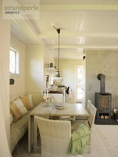 Weiß getäfeltes Wohnzimmer mit Esstisch und Holzofen