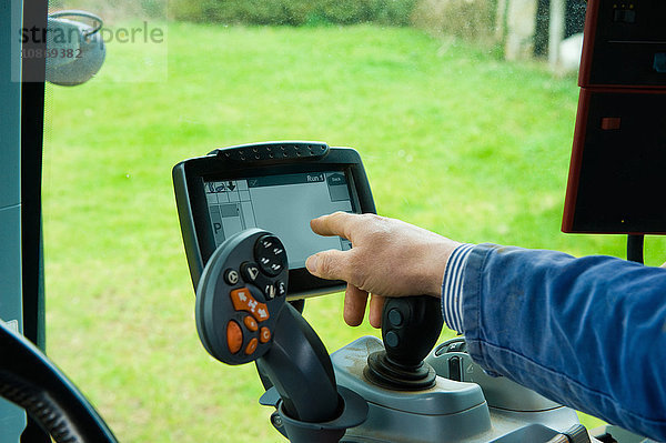 Hand des Landwirts mit Computer-Touchscreen im Traktor