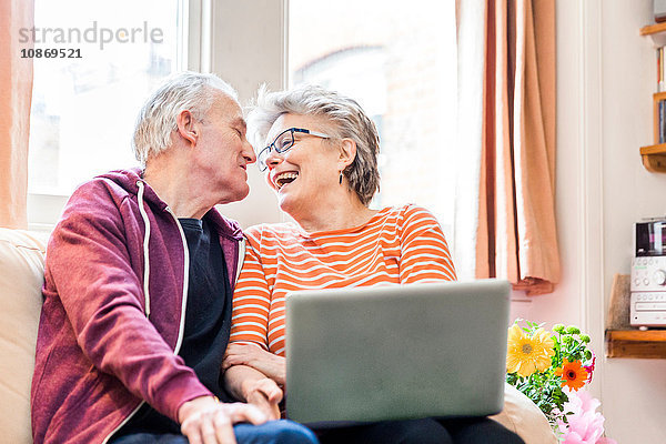 Älteres Ehepaar auf Wohnzimmer-Sofa mit Laptop