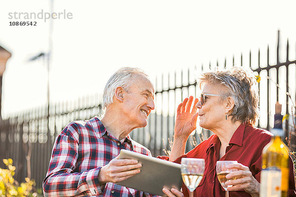 Älteres Ehepaar auf dem Dachgarten der Stadt mit digitalem Tablet