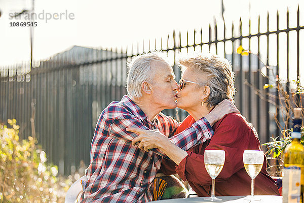 Romantisches Seniorenpaar küsst sich auf dem Dachgarten der Stadt