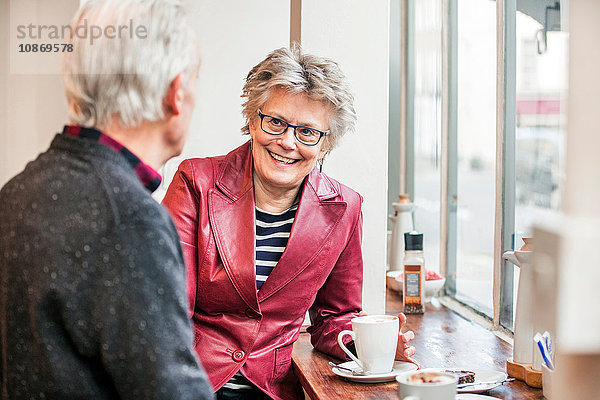 Älteres Ehepaar plaudert am Fensterplatz eines Cafés