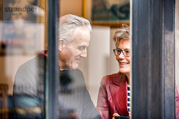 Älteres Ehepaar sitzt am Café-Fensterplatz und plaudert
