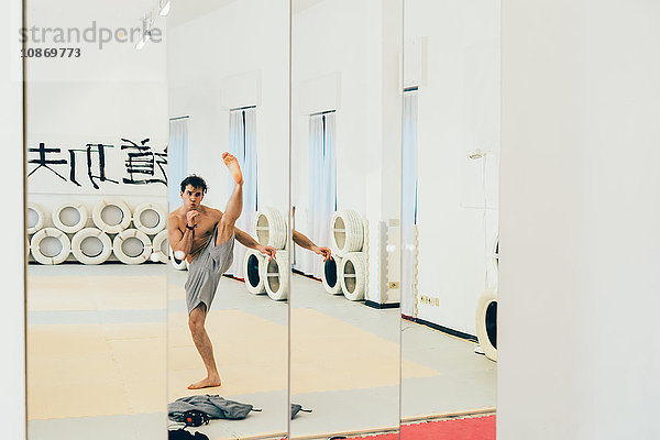 Spiegelbild eines Kampfsportlers in der Turnhalle beim Kicken