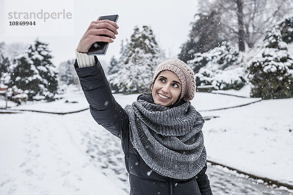 Frau auf schneebedeckter Landschaft mit Smartphone zum Selbermachen