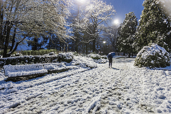 Frau geht abends auf schneebedeckter Landschaft