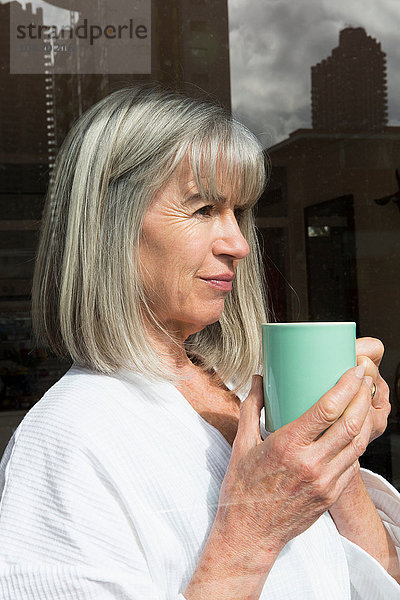 Frau mit Becher neben dem Fenster