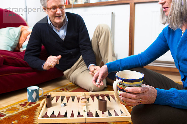 Paar spielt Backgammon am Boden