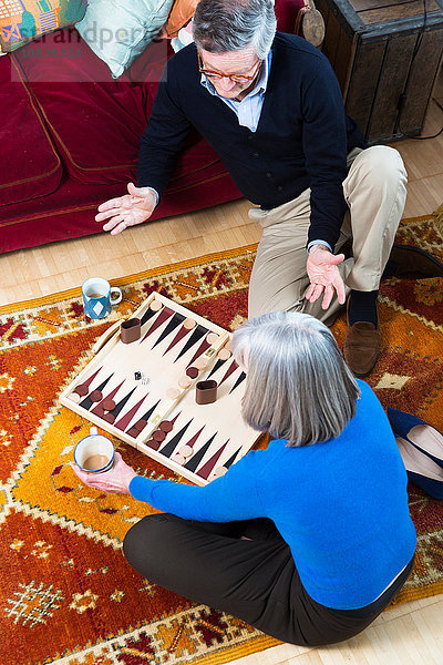 Paar spielt Backgammon am Boden