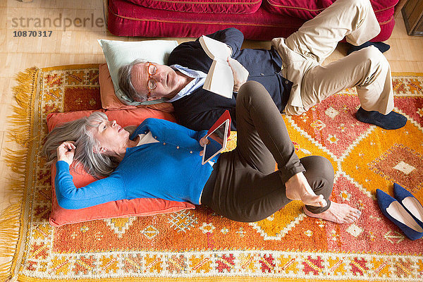Ehepaar liest Buch auf dem Boden