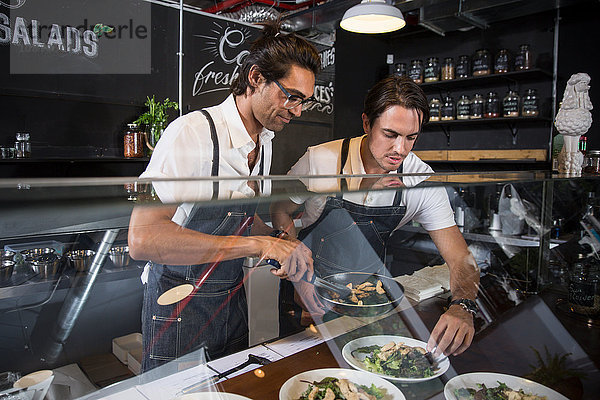 Gastronomen bei der Zubereitung von Salat hinter der Bedienungstheke