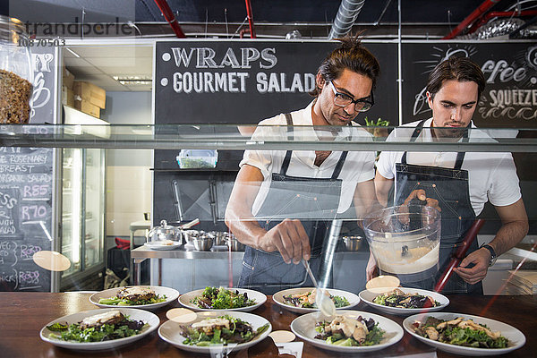 Gastronomen bei der Zubereitung von Salat hinter der Bedienungstheke