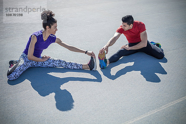 Junger Mann und Frau trainieren  Zehen auf Asphalt berühren