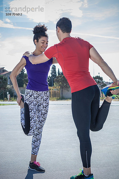 Junger Mann und Frau trainieren gemeinsam in einer Sportanlage