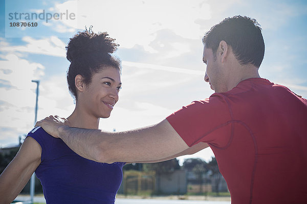 Mann unterrichtet junge Frau beim Training in Sportanlage