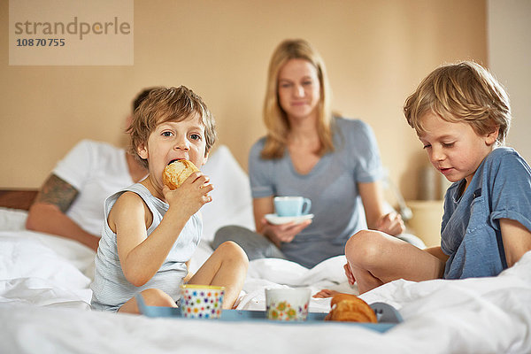 Jungen frühstücken im Bett der Eltern