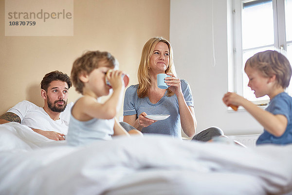 Jungen frühstücken im Bett der Eltern