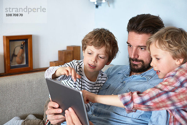 Vater und Söhne auf Sofa mit digitalem Tablett
