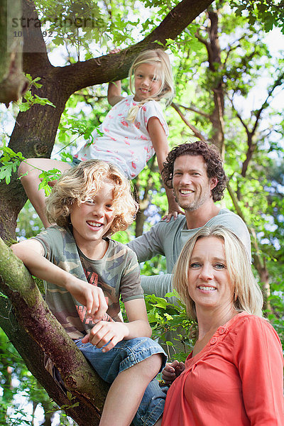Familie im Waldkletterbaum schaut lächelnd in die Kamera