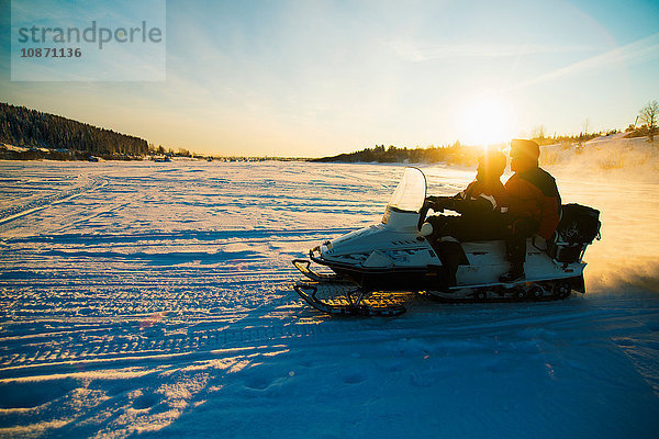 Menschen auf Schneemobilen in verschneiter Landschaft