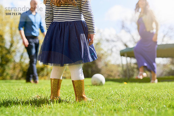 Niederer Teil eines Mädchens im Garten mit Familie beim Fussballspielen