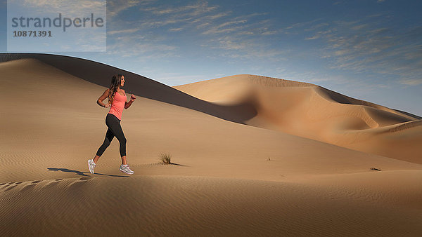Frau joggt auf Wüstensanddüne  Leeres Viertel Wüste  Abu Dhabi  Vereinigte Arabische Emirate