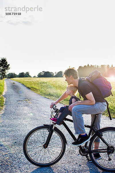 Vater und kleine Tochter fahren zusammen Fahrrad