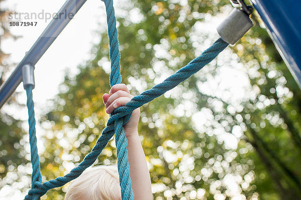 Kleinkind auf Klettergerüst im Park  Fokus auf Hand