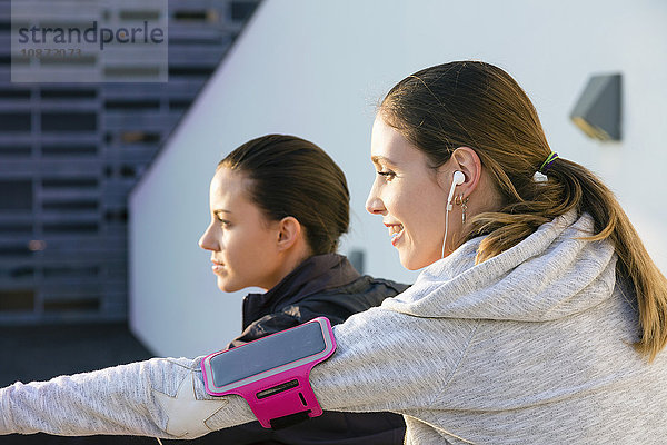 Junge Frau im Freien  trägt Kopfhörer und mp3-Player am Arm