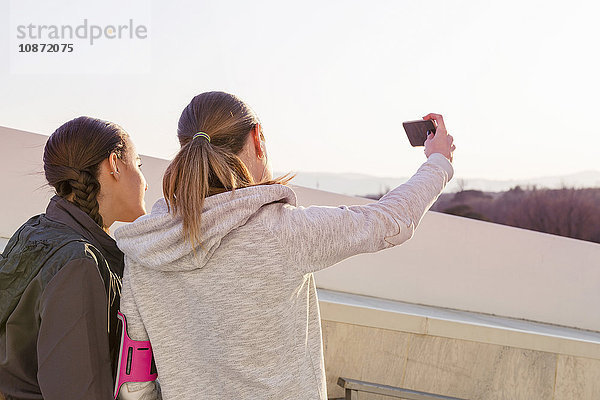 Zwei Freundinnen im Freien  Selbstporträt mit Smartphone  Rückansicht