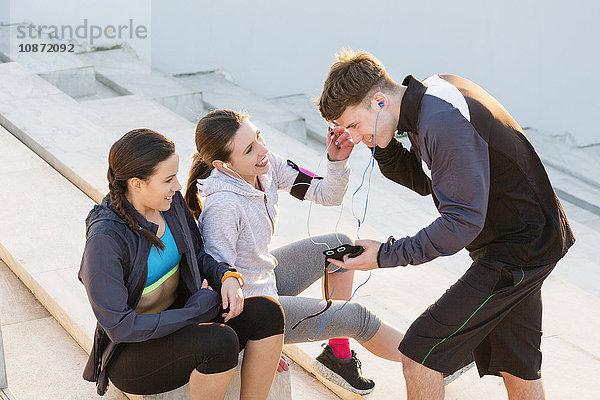 Drei Freunde machen eine Pause vom Sport und hören Musik auf mp3-Playern