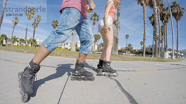 Blick von der Hüfte abwärts auf ein Paar beim Rollerbladen am Venice Beach  Kalifornien  USA