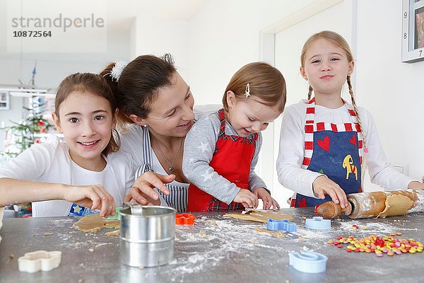 Mädchen mit Mutter an der Küchentheke  die Kekse lächelnd backen