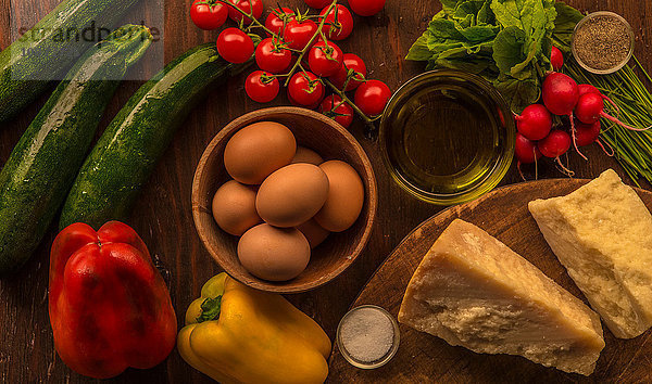 Draufsicht auf rohe und zubereitete Lebensmittel  Parmesan  Eier und Gemüse