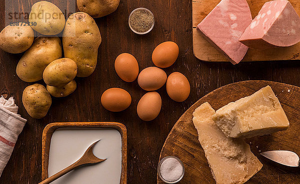 Draufsicht auf rohe und zubereitete Lebensmittel  Parmesan  Milch  Eier und Kartoffeln