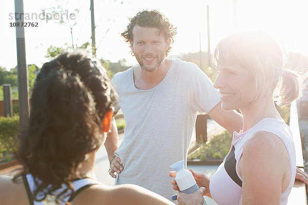 Zwei Frauen und ein Mann trainieren  plaudern im Sonnenlicht