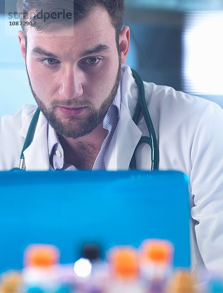 Arzt liest medizinische Testergebnisse von Patienten auf Laptop  Proben im Vordergrund