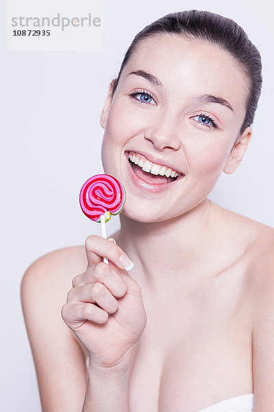 Porträt einer schönen jungen Frau mit rosa Lolli in der Hand