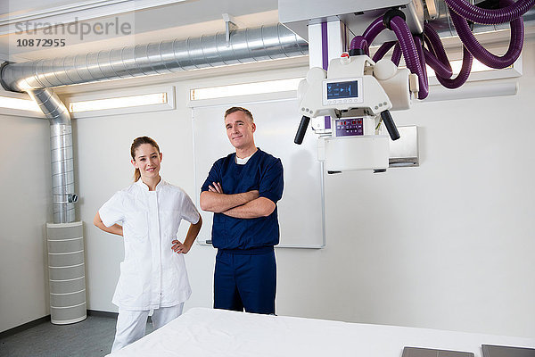 Porträt eines Arztes und einer Krankenschwester neben einer medizinischen Röntgenanlage im Krankenhaus