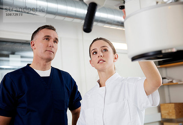 Arzt und Krankenschwester beim Einstellen medizinischer Röntgengeräte