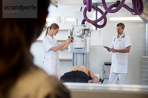 Ärzte bereiten Ausrüstung für die Röntgenaufnahme eines männlichen Patienten vor